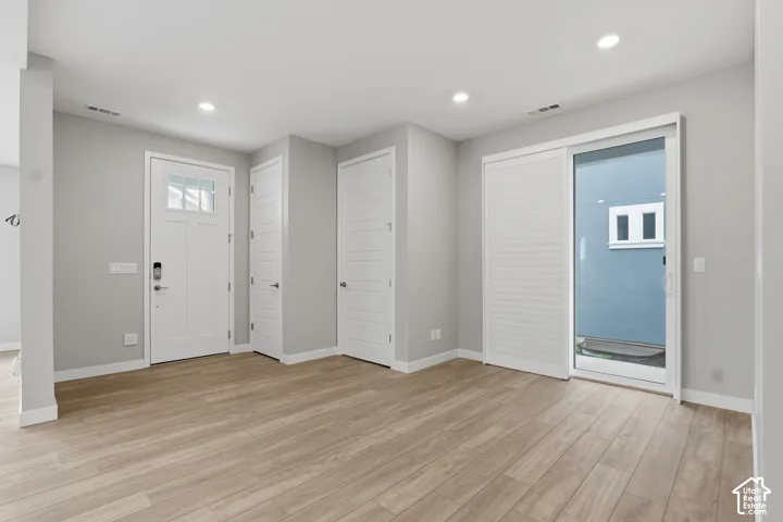 Neutral-toned interior featuring wood-finish flooring, recessed lighting, white paneled doors, and a sliding glass door