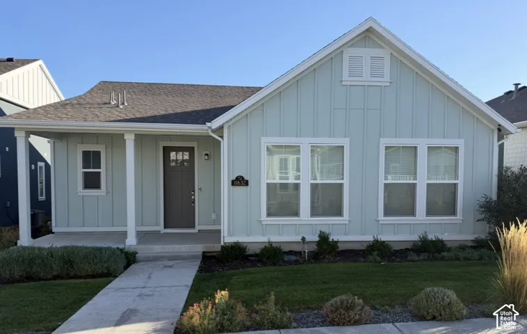 Single-story exterior featuring board-and-batten siding, a covered front porch, an asphalt shingle roof, and a gable vent