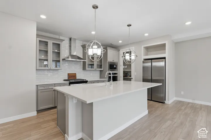 Kitchen featuring a center island with a stone-finish countertop, stainless steel appliances, a tile backsplash, glass-front cabinetry, and pendant lighting