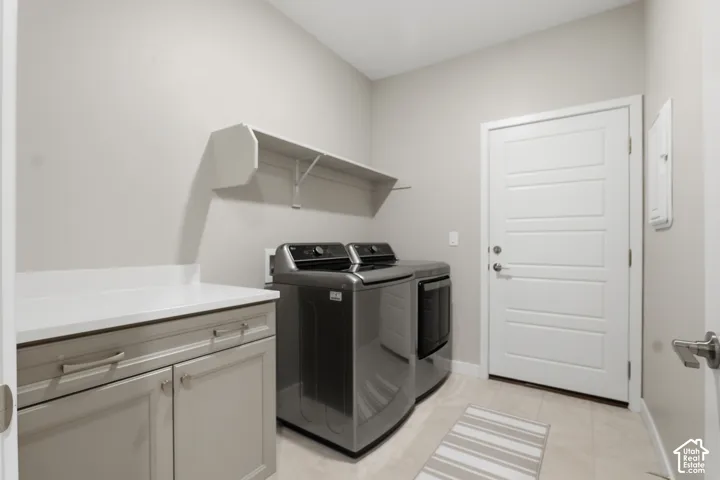 Laundry room featuring neutral-toned cabinetry, solid-surface countertop, built-in shelving, tile flooring, and a paneled exterior door