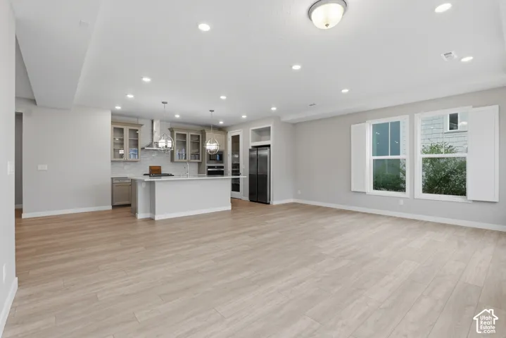 Open-concept interior featuring light wood-finish flooring, recessed lighting, and a kitchen equipped with a quartz-topped center island, custom cabinetry, and stainless steel appliances