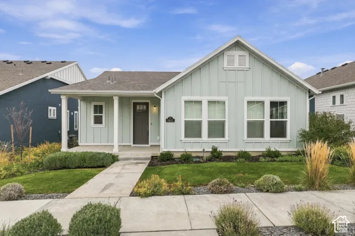 Single-story residence featuring vertical board-and-batten siding, a covered front porch with column supports, a multi-gable roofline, and low-maintenance xeriscaping