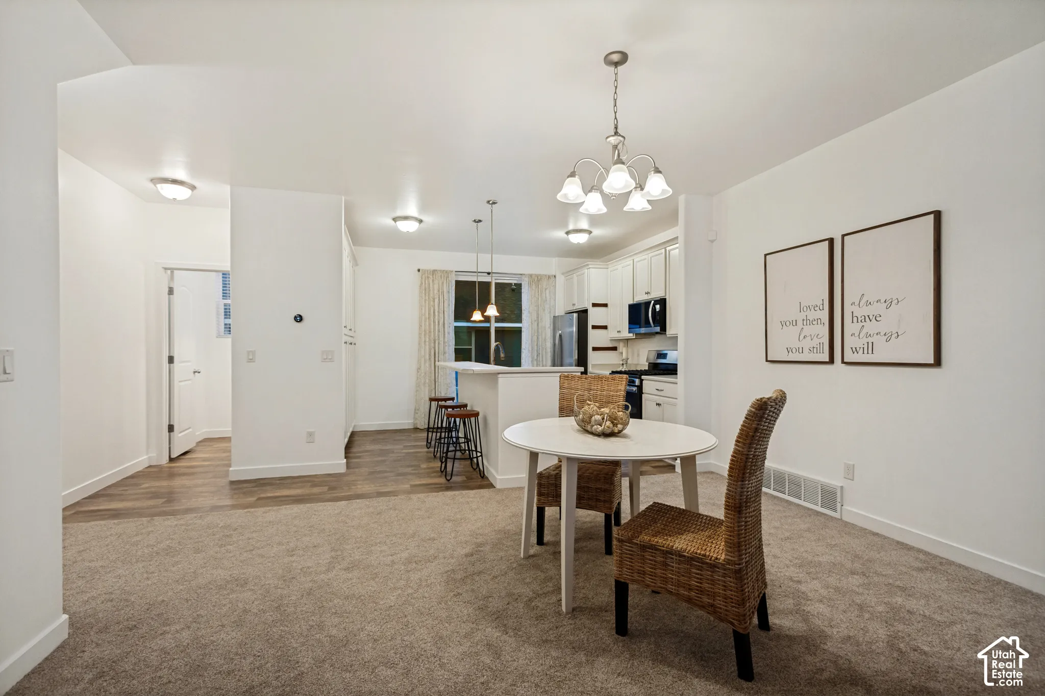 Kitchen featuring a raised breakfast bar, white cabinetry, integrated lighting, carpeted flooring, and hard-surface flooring