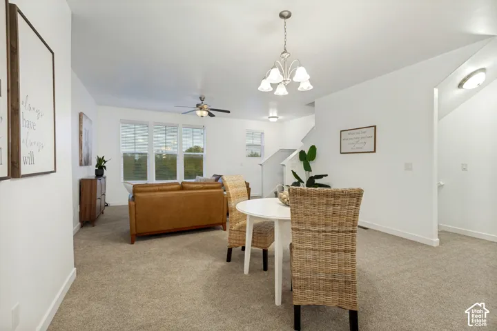 Open-concept interior featuring neutral wall tones, wall-to-wall carpeting, a multi-arm chandelier, and triple-pane window configuration