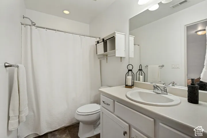 Bathroom featuring a white vanity with a composite countertop and integrated sink, full-width wall mirror, wall-mounted storage cabinetry with sliding doors, and a shower-tub combination with a polished chrome faucet