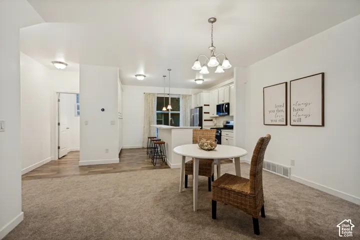 Kitchen featuring a raised breakfast bar, white cabinetry, integrated lighting, carpeted flooring, and hard-surface flooring