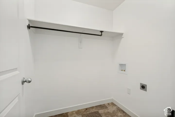 Utility space featuring tile flooring, built-in shelving, an industrial-style hanging rod, and dedicated washer and dryer hookups