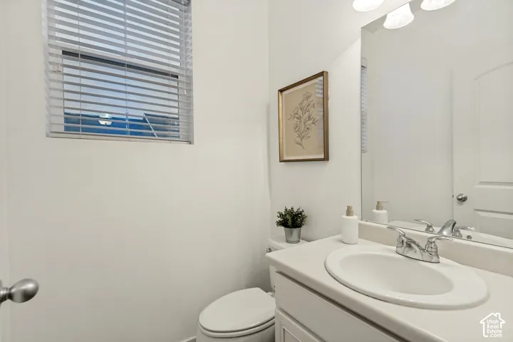 Bathroom featuring a vanity with a white countertop and integrated sink, a large wall-mounted mirror, polished chrome dual-handle faucet, and horizontal slatted blinds