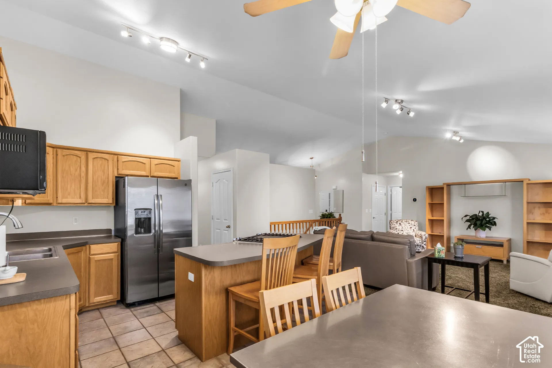 Kitchen featuring oak cabinetry, solid-surface countertops, tile flooring, vaulted ceilings, and a built-in shelving unit