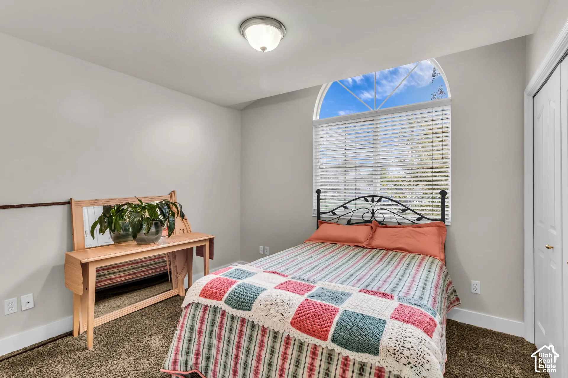 Arched upper window with horizontal blinds, neutral wall paint, carpeting, flush-mount ceiling lighting, and double-door closet
