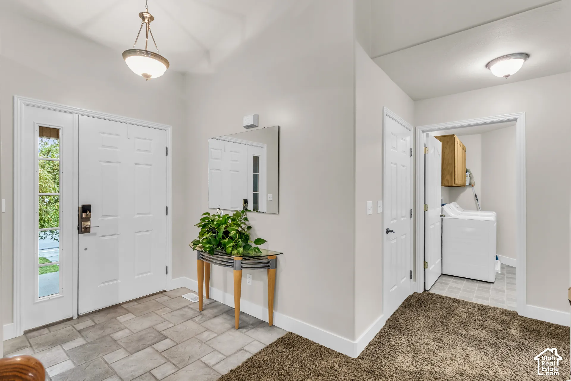 Entryway featuring tile flooring, a multi-pane glass entry door, a polished metal-finish pendant light, and a built-in flush-mount ceiling light