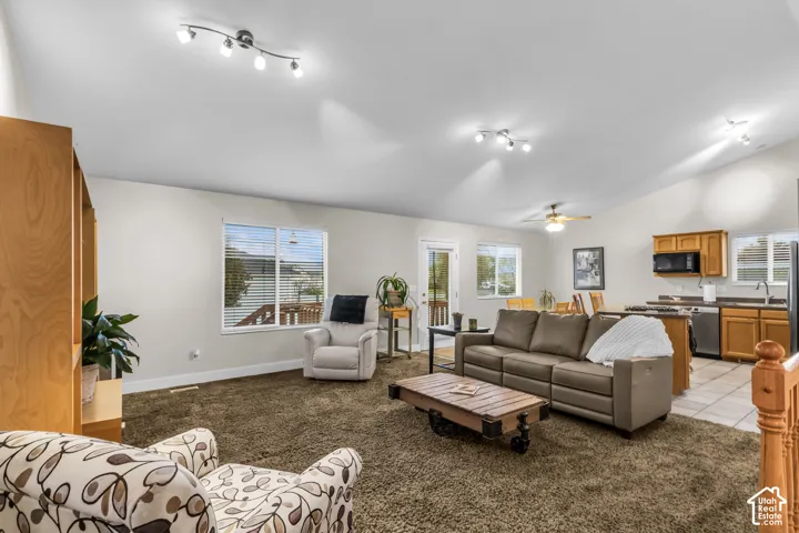 Open-concept floor plan featuring vaulted ceilings, multiple track lighting fixtures, and a kitchen with wood cabinetry