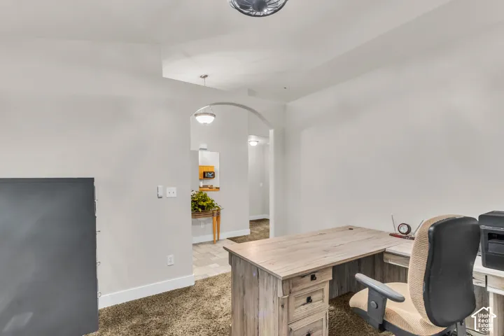Room featuring an arched architectural opening, vaulted ceiling, and neutral wall tones
