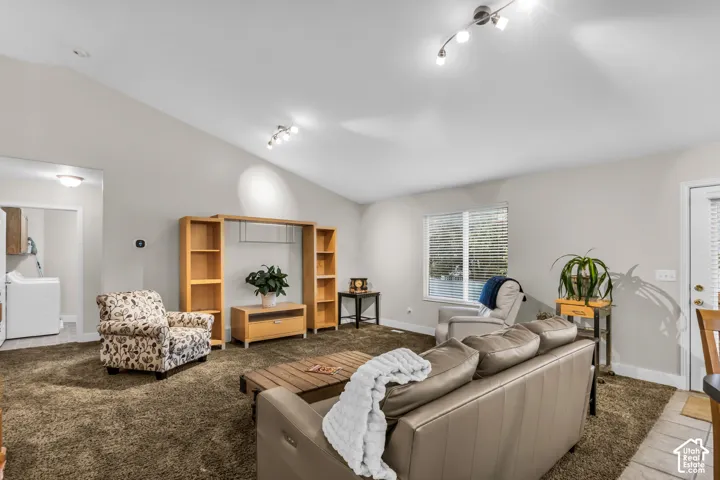 Vaulted ceilings, built-in shelving unit, multi-directional track lighting, and window with horizontal blinds