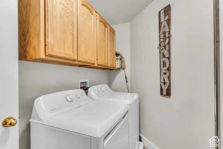 Laundry area featuring wall-mounted wood-finish cabinetry and dedicated plumbing connections