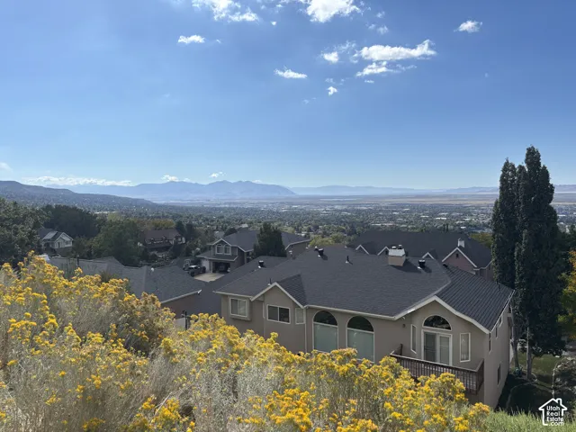 Elevated perspective featuring expansive valley scenery, distant mountain ranges, and architectural details including arched window accents and a tiered exterior deck