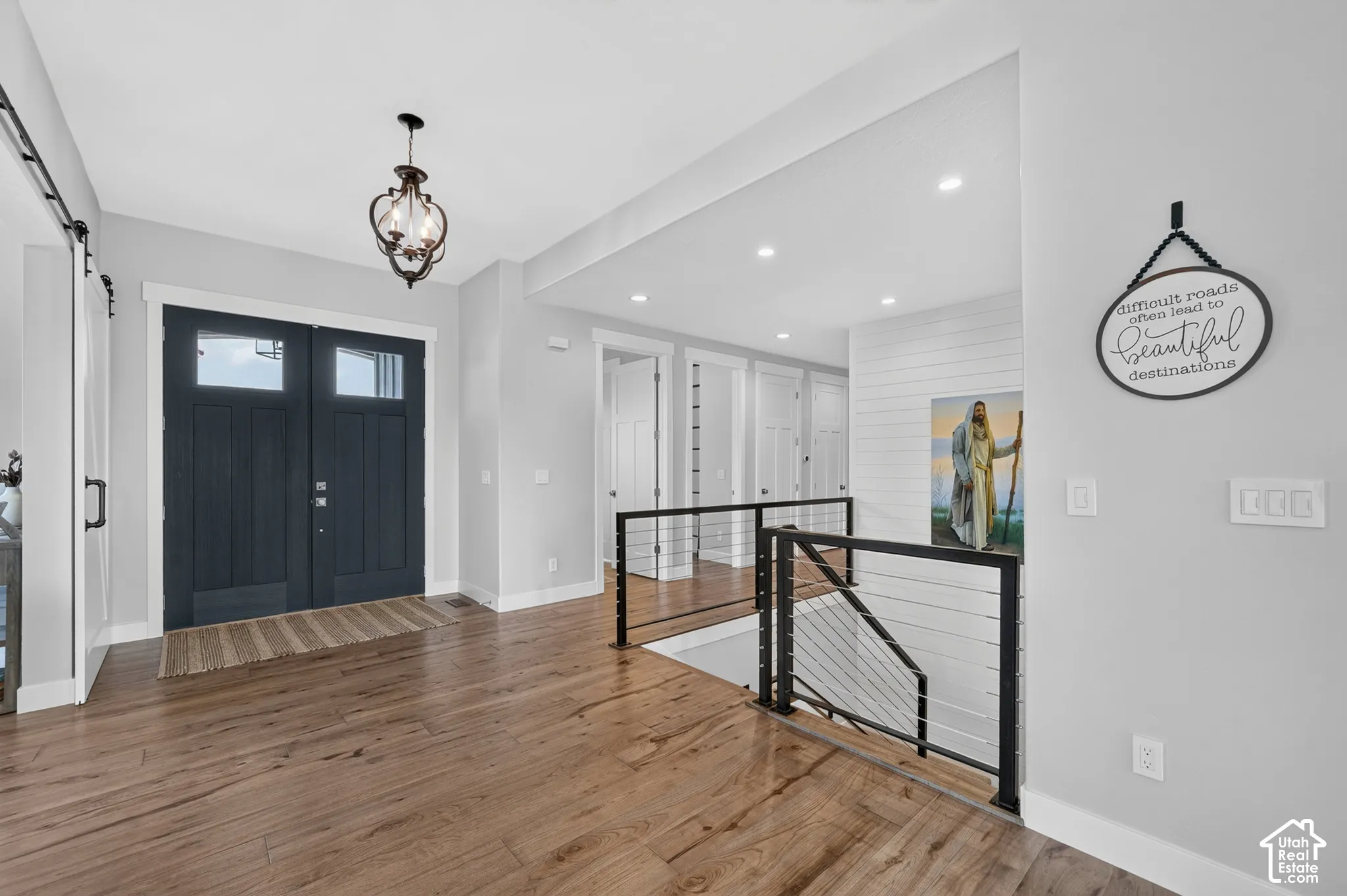 Double entry doors featuring a dark finish, wood-finish flooring, metal railing with horizontal cable infill, and shiplap wall accents