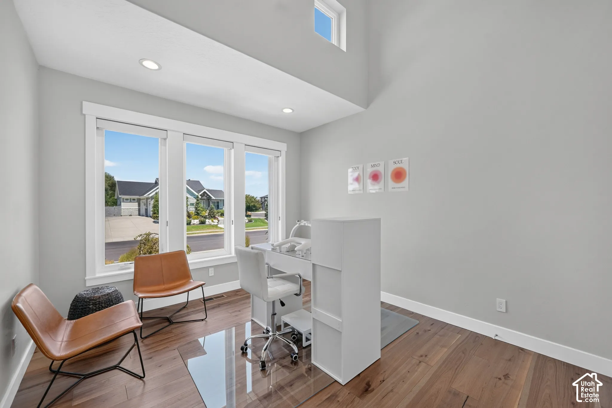 High-ceilinged room with wood-finish flooring, recessed lighting, expansive triple-pane windows, and a clerestory window