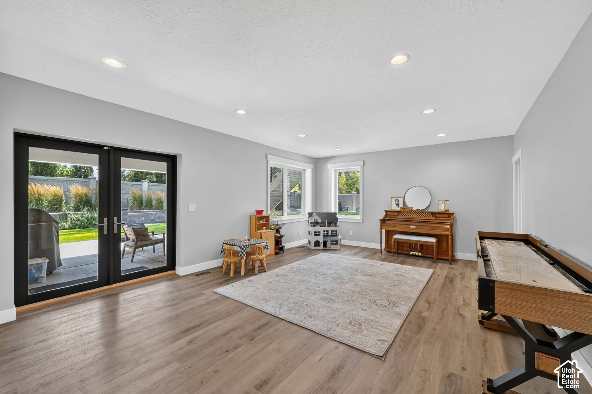 Open-concept room featuring wood-finish flooring, recessed lighting, and black-framed glass paneled exterior doors