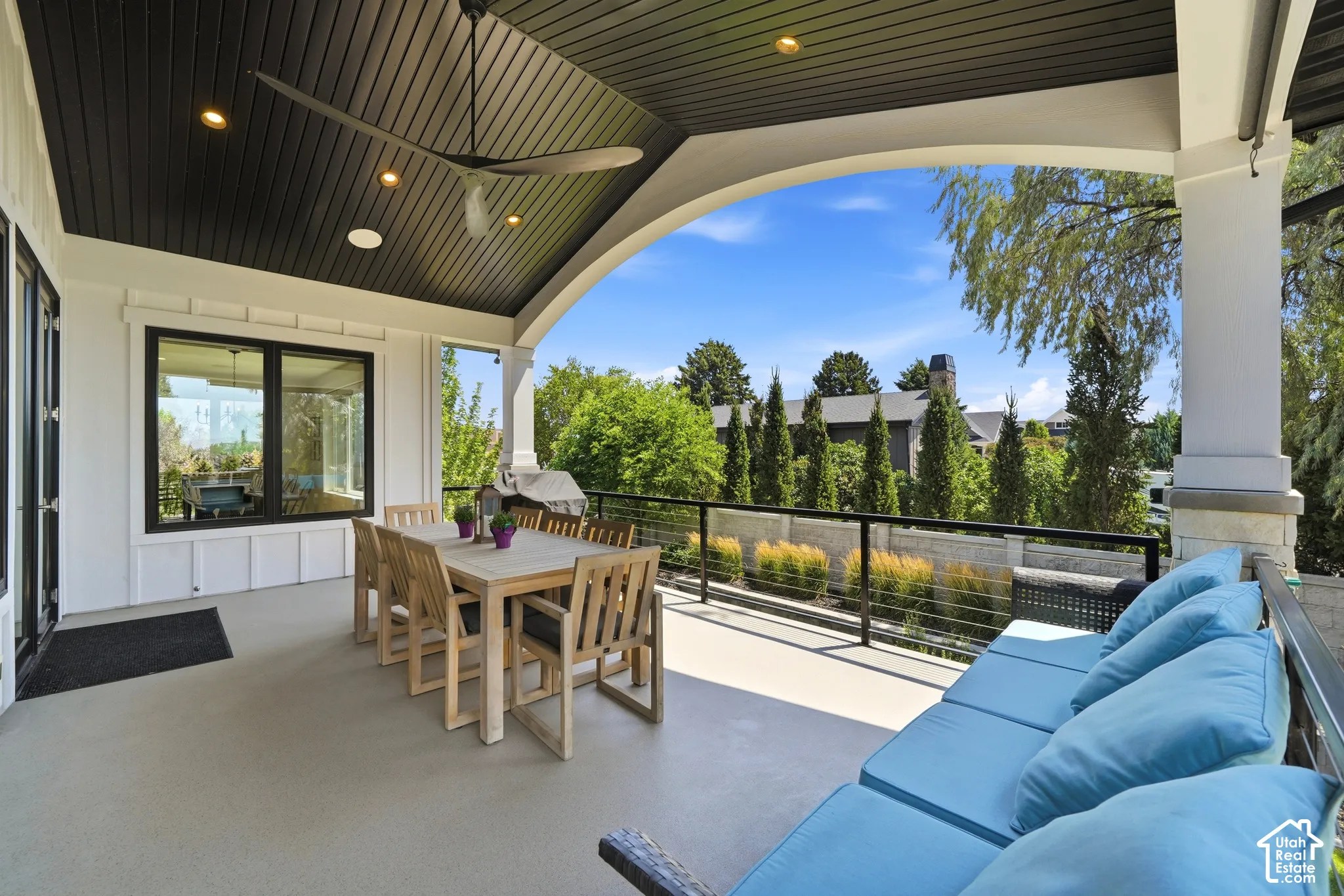 Covered patio featuring a vaulted ceiling with dark horizontal wood-finish planks, recessed lighting, a ceiling fan, and black metal railings with thin horizontal cabling