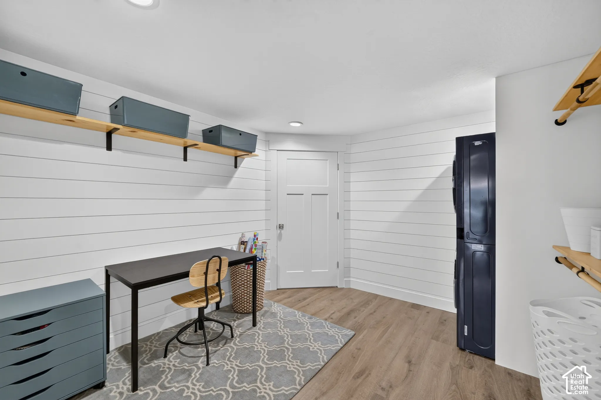 Horizontal plank wall paneling, wood-finish flooring, recessed lighting, and built-in wood shelving units
