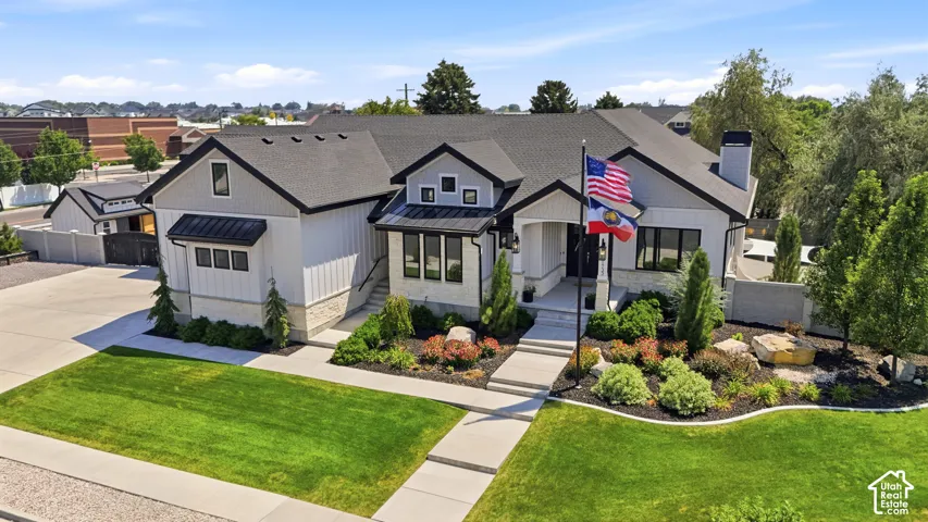 Modern exterior featuring light-toned board-and-batten siding, stone masonry accents, a pitched roofline with dark metal roofing details, and a concrete walkway leading to an inset entryway