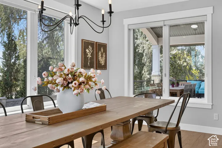 Dining area featuring expansive windows, wood-finish flooring, a wrought-iron chandelier, and a covered exterior balcony