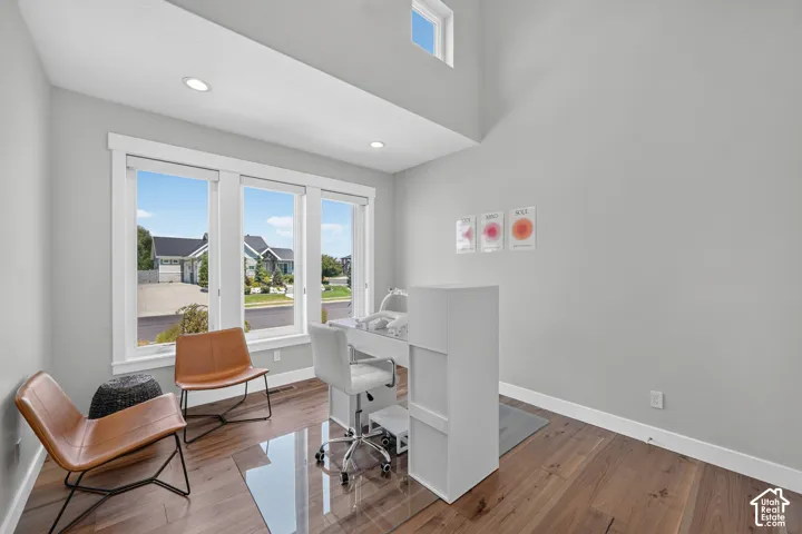 High-ceilinged room with wood-finish flooring, recessed lighting, expansive triple-pane windows, and a clerestory window