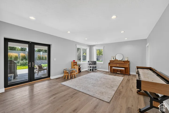 Open-concept room featuring wood-finish flooring, recessed lighting, and black-framed glass paneled exterior doors