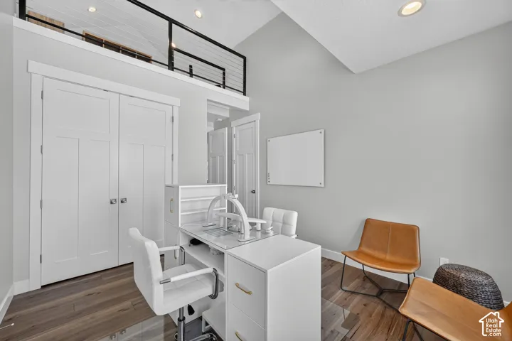 Vaulted ceilings, wood-finish flooring, recessed lighting, and a loft area featuring a black metal railing