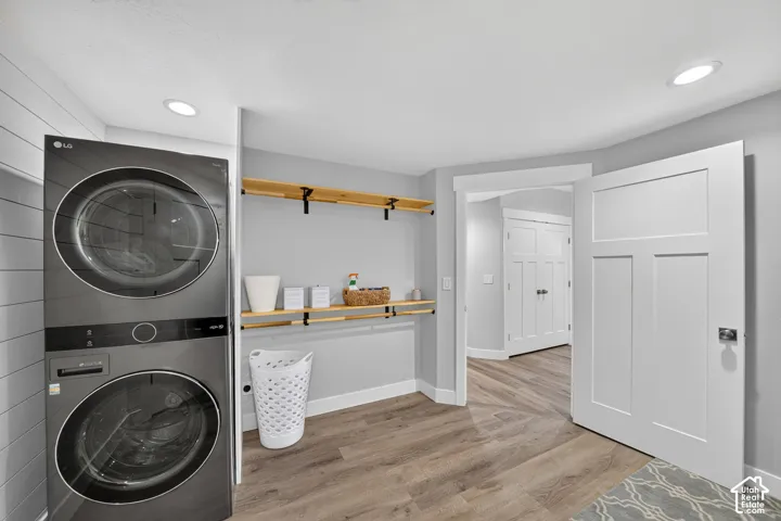 Laundry area featuring wood-finish flooring, white shiplap wall accent, open-shelf wood shelving with matte black supports, and recessed lighting