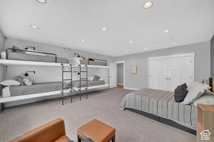 Built-in double-stacked bunk beds with iron ladder hardware, recessed ceiling lighting, shiplap wall detailing, and double-door closet with shaker-style panels