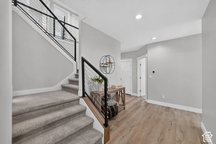 Staircase featuring a black metal railing with horizontal cable infill and wood-finish flooring