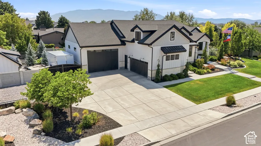 Multi-gabled exterior featuring board-and-batten siding, stone masonry accents, a paved multi-car driveway, and mountain backdrop