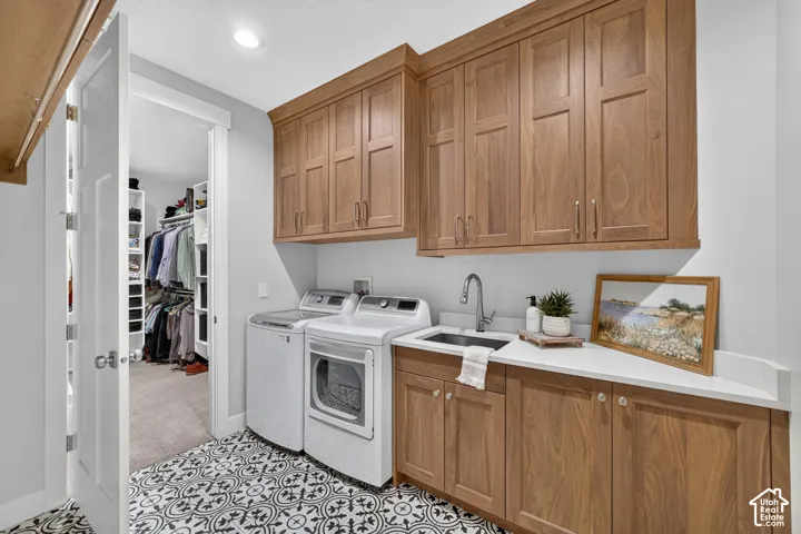 Laundry room featuring extensive upper and lower wood cabinetry, quartz countertops, an undermount sink with a gooseneck faucet, and patterned tile flooring