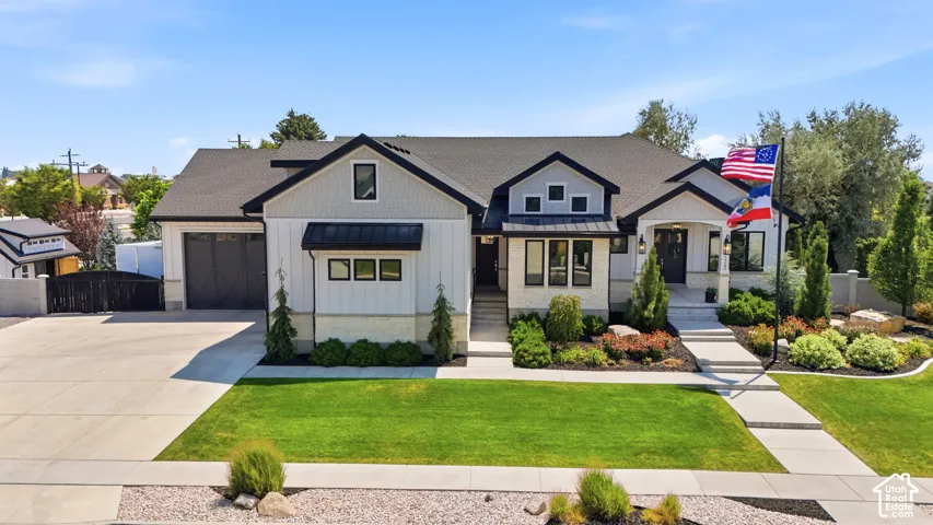 Exterior featuring board-and-batten siding, stone masonry accents, a metal roof gable detail, multi-car garage with carriage-style doors, and a covered front porch