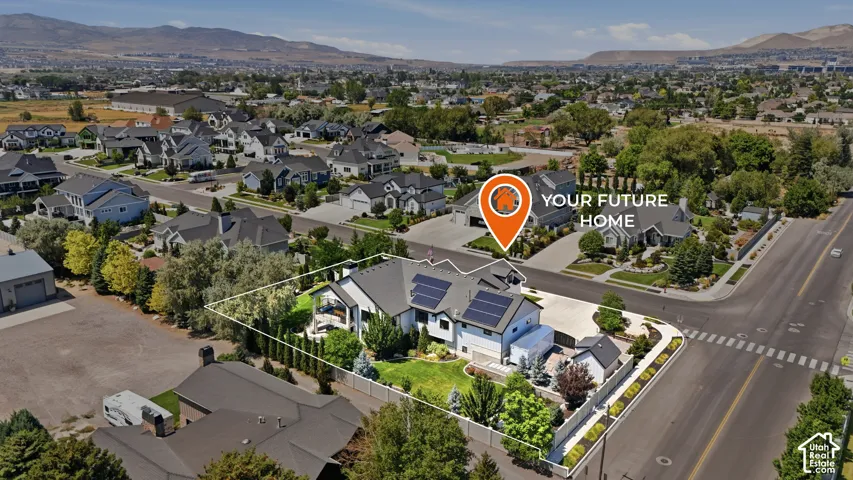 Aerial perspective of a multi-story residence featuring solar panels, a fenced backyard, a paved driveway, and a covered patio area
