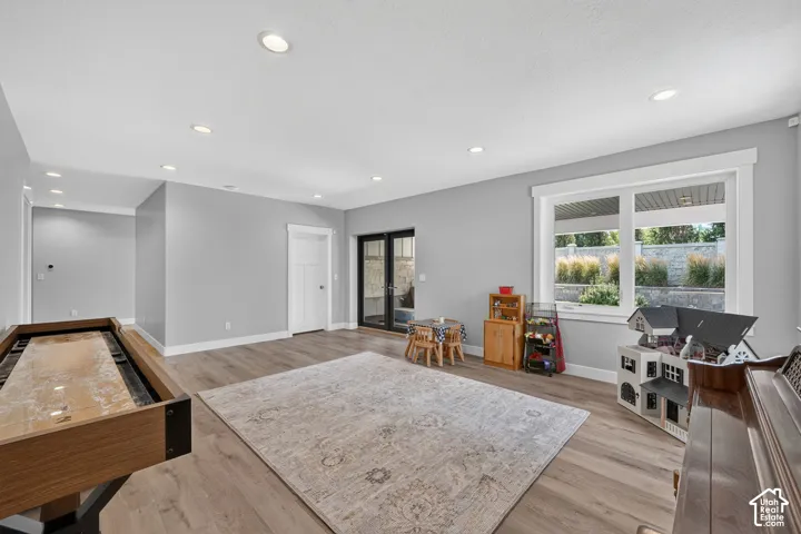 Open living area featuring wood-finish flooring, neutral wall paint, recessed lighting, expansive multi-pane window, and glass-paneled exterior doors
