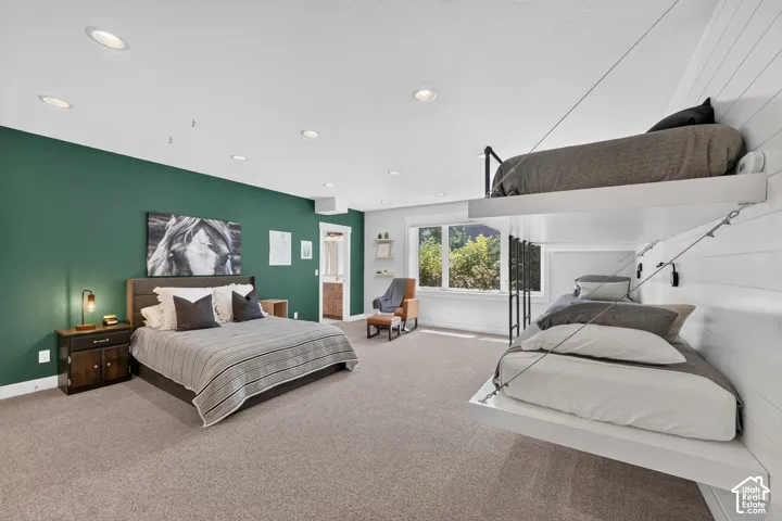 Spacious interior featuring built-in suspended bunk bed shelving, white horizontal shiplap wall paneling, a dark green accent wall, recessed lighting, and wall-to-wall carpeting