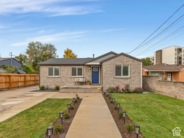 Brick exterior featuring a concrete walkway with built-in path lighting, a covered entryway, and a concrete driveway