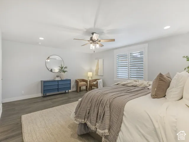 Bedroom featuring wood-finish flooring, recessed lighting, a ceiling fan with integrated glass light fixtures, and windows dressed with plantation shutters