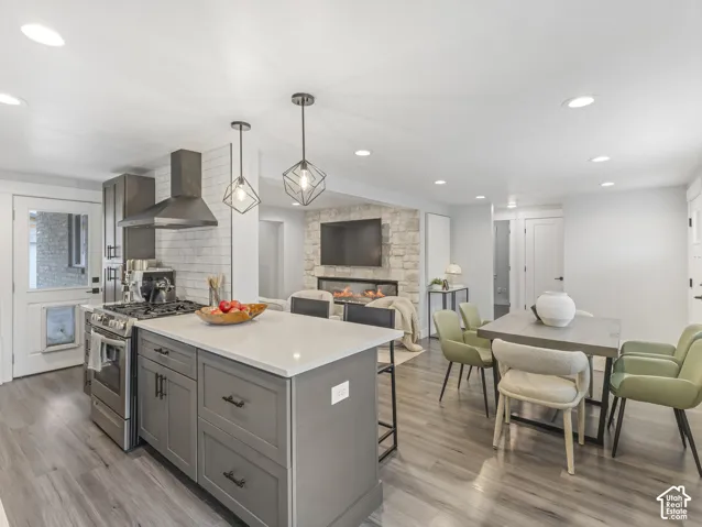 Kitchen featuring a center island with a solid-surface countertop, cabinetry with matte black hardware, stone-finished fireplace, recessed lighting, and wood-finish flooring