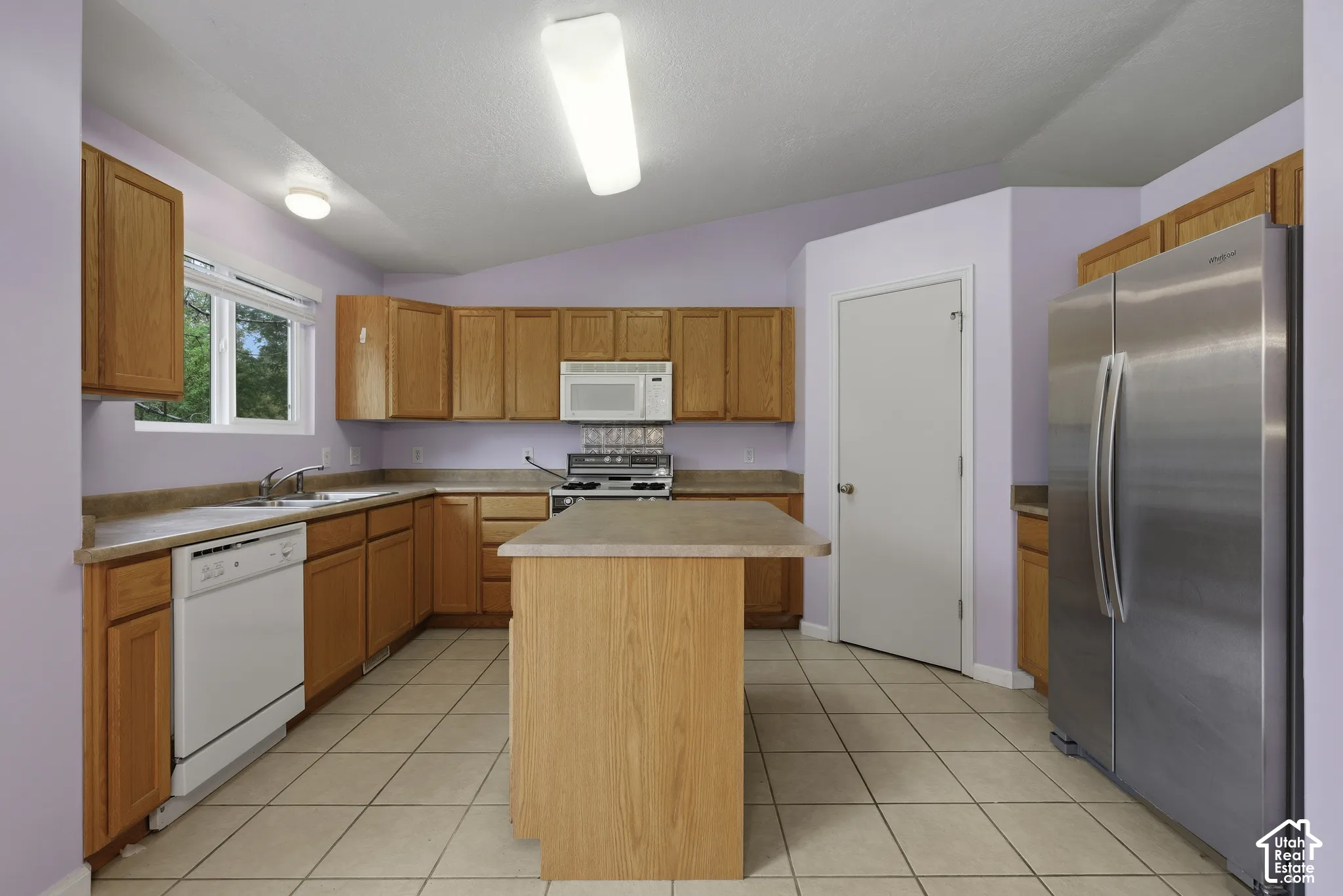 Kitchen with center island, corner pantry and stainless steel refrigerator