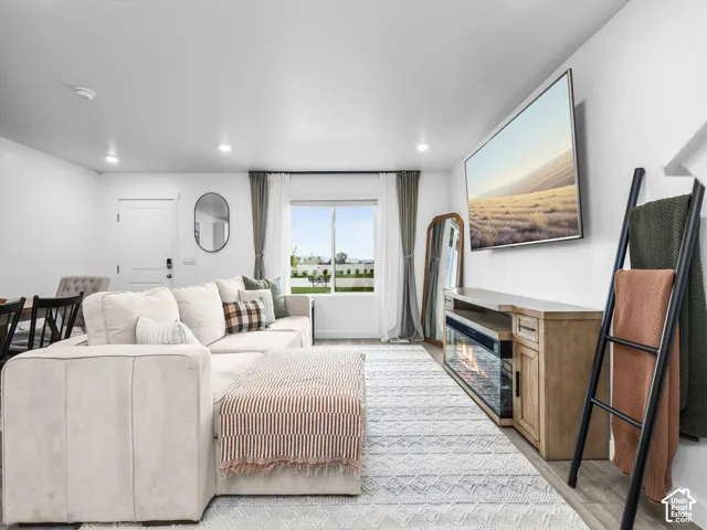 Living area featuring recessed lighting, wood-finish flooring, a single-pane window, and an integrated electric fireplace console