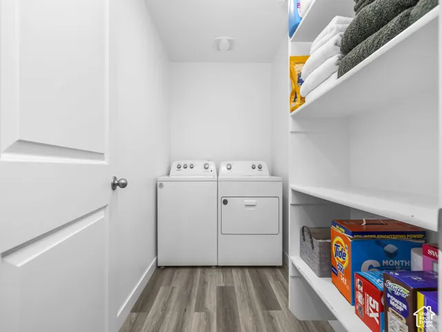 Laundry room featuring wood-finish flooring, multi-level built-in shelving, and a solid-core swing door