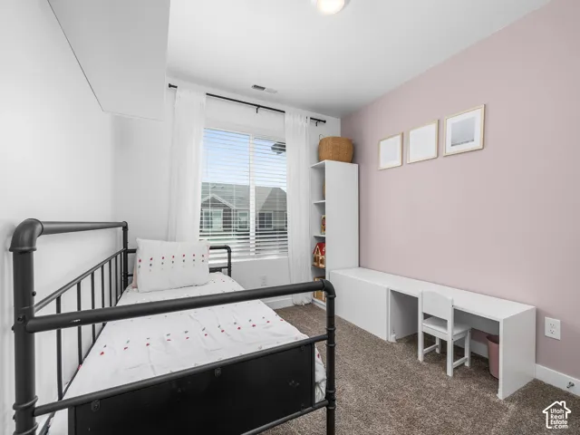 Room featuring wall-to-wall carpeting, a large window with horizontal blinds, and custom built-in cabinetry including a desk surface and vertical shelving