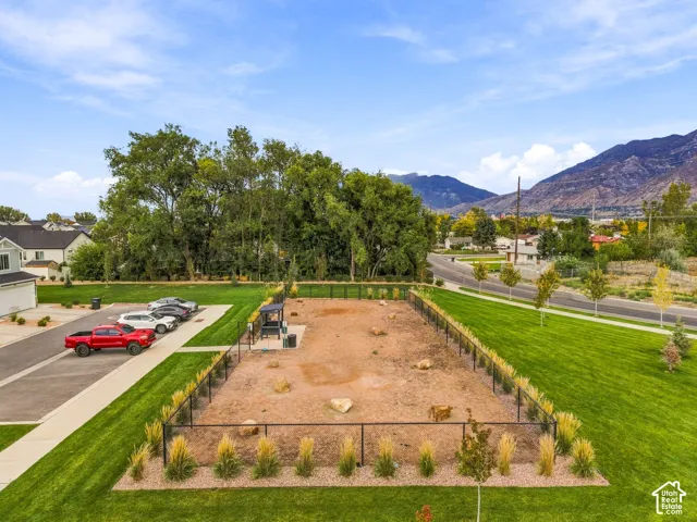 Fenced outdoor recreation area featuring gravel surfacing, boulder accents, and a covered pavilion with mountain backdrop