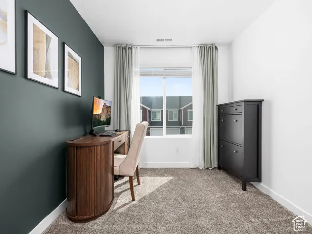 Room featuring a dark-toned accent wall, neutral carpeting, and a large window with white casing