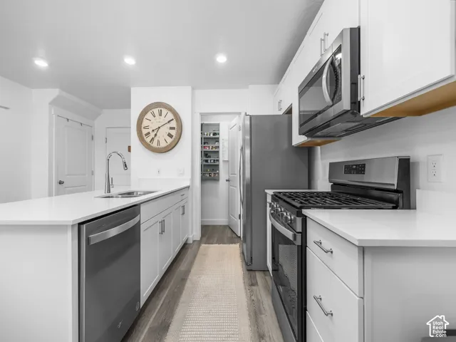 Kitchen featuring white shaker-style cabinetry, quartz countertops, wood-finish flooring, recessed lighting, and stainless steel appliances