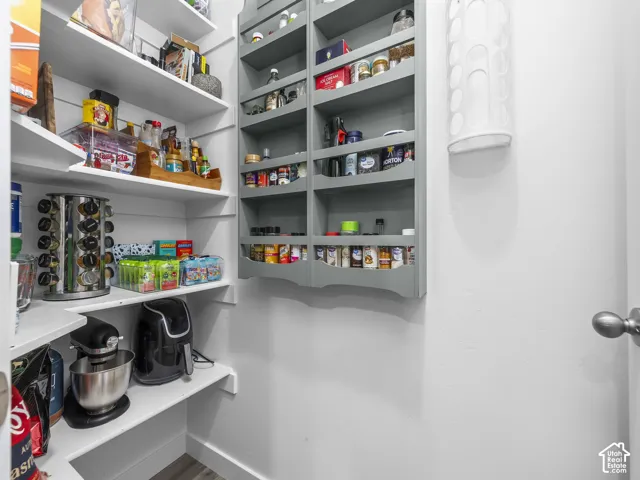 Walk-in pantry featuring white shelving, wall-mounted grey storage rack, and neutral walls
